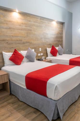 two beds in a hotel room with red pillows at Hotel Hidalgo in Querétaro