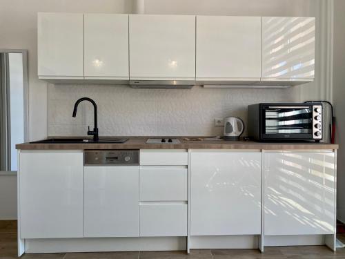 een keuken met witte kasten, een wastafel en een magnetron bij Pearl Apartment Pula in Pula