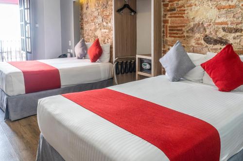 a hotel room with two beds with red and white sheets at Hotel Hidalgo in Querétaro