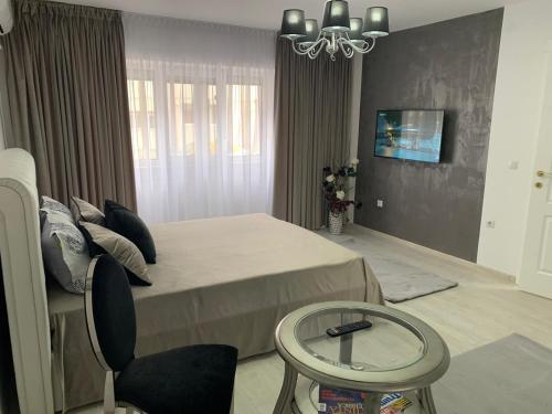 a bedroom with a bed and a table and a chair at Leon Apartment in Brăila