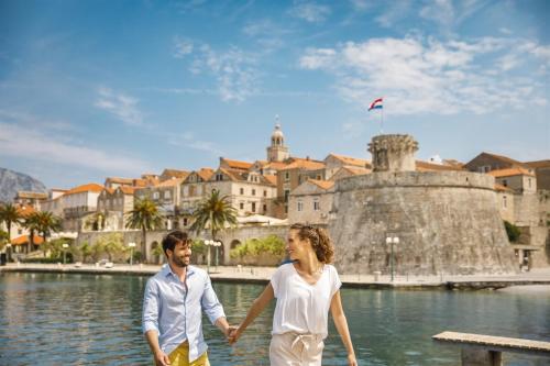 a man and a woman holding hands while walking in front of a castle at Aminess Vival Port9 Residence in Korčula