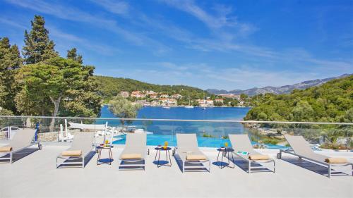 a row of lounge chairs on a patio next to a lake at Aminess Vival Port9 Residence in Korčula