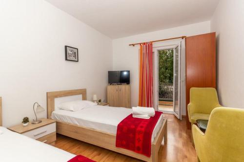 a bedroom with a bed and a chair and a window at Apartments Forte Mare in Herceg-Novi