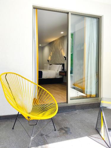 a yellow chair sitting in front of a bedroom at Ramë Hotel Boutique in Guadalajara