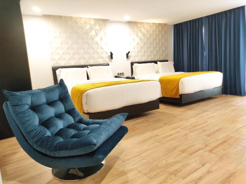a hotel room with two beds and a chair at Ramë Hotel Boutique in Guadalajara