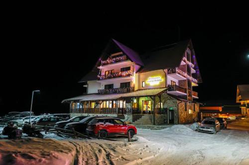 a red car parked in front of a building in the snow at Poarta Raiului in Tău Bistra