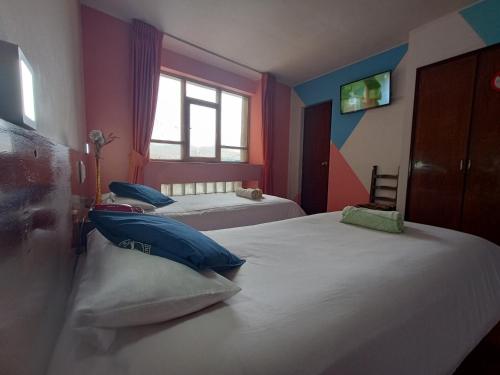 a bedroom with two beds with blue pillows and a window at Isabela Hotel in La Paz