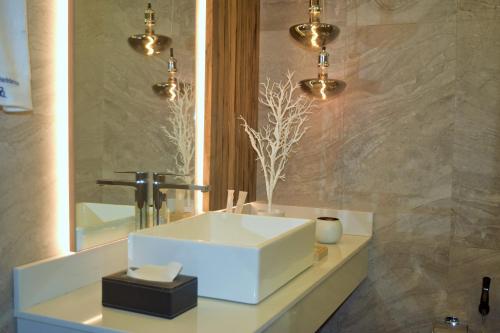 a bathroom with a white sink and a mirror at Montecito Apartments in Accra