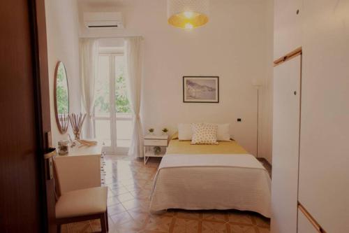 a bedroom with a bed and a desk and a window at L'eco delle sirene in Amalfi