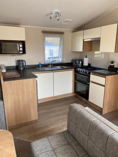 a kitchen with white cabinets and black appliances at Dixons den in Swarland