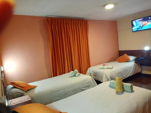 a room with two beds and a tv on the wall at Isabela Hotel in La Paz