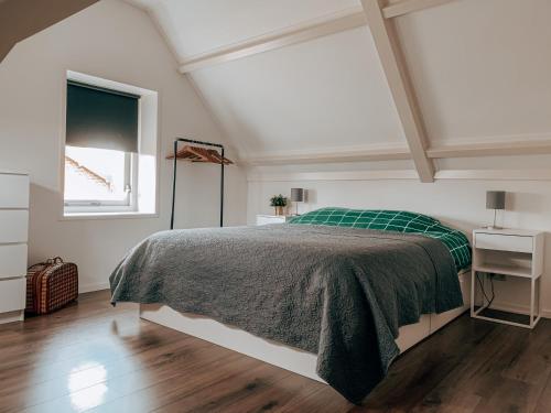 een slaapkamer met een bed met een groene deken en een raam bij Het Korenhuus in Lewedorp