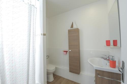 Baño blanco con lavabo y aseo en Charmant 2 pièces proche de Paris, en Villeneuve-la-Garenne