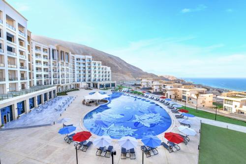 a large pool with chairs and umbrellas on a balcony at Tolip Resort El Galala Hills in Ain Sokhna