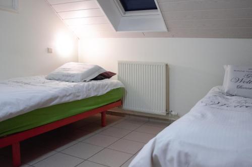 a bedroom with two beds and a radiator at Hageland Vakantieverblijf in Holsbeek