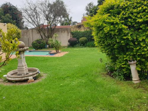 a yard with a garden with a bird bath in the grass at Matina Guest House in Johannesburg