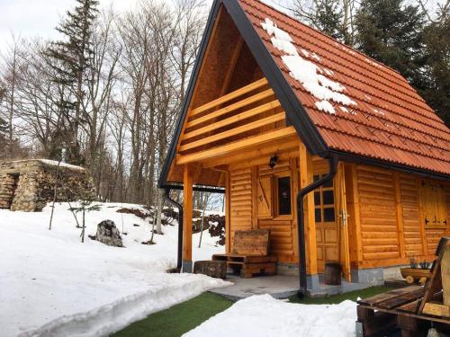 a wooden cabin with a red roof in the snow at Dren Chalet Lux - Banjska stena in Perućac