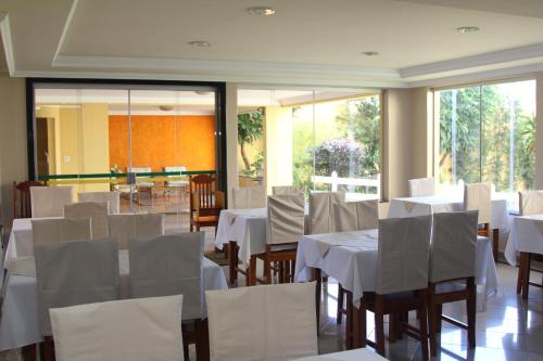 a dining room with white tables and white chairs at Hotel Jaguar in Uberaba