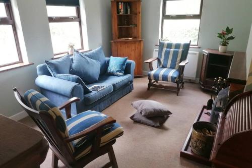 a living room with a blue couch and two chairs at Harbourside House Glengarriff in Glengarriff