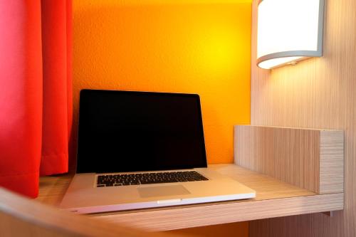 a laptop computer sitting on top of a wooden shelf at Premiere Classe Montauban in Montauban