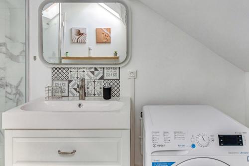 a bathroom with a sink and a washing machine at Escale pro & détente à 3 min de la gare - Parking - WIFI - PS4 in Corbeil-Essonnes