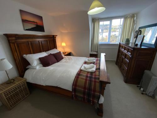 a bedroom with a large bed and a dresser at Beach View Cottage in Isle of Gigha