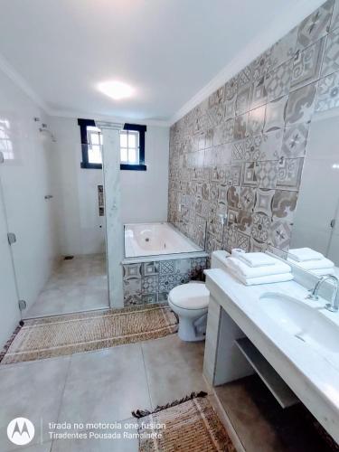 a bathroom with a tub and a toilet and a sink at Tiradentes Pousada Ramalhete in Tiradentes