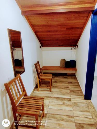 a room with two wooden chairs and a bench at Tiradentes Pousada Ramalhete in Tiradentes