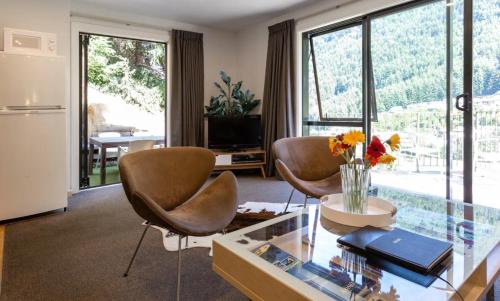 a living room with two chairs and a glass table at Alpine Retreat in Queenstown