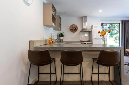 a kitchen with a counter with four bar stools at Alpine Retreat in Queenstown