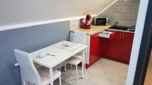 a small kitchen with a white table and red cabinets at Le petit Luxembourg in Montignies-sur-Sambre