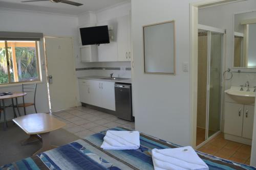 a kitchen with white cabinets and a sink and a table at Yamba Motor Inn in Yamba