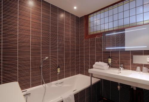 a bathroom with a bath tub and a sink at Le Grand Hotel in Tours