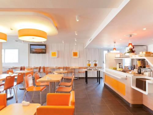 a restaurant with tables and chairs and a bar at Ibis Budget Cergy St Christophe in Cergy