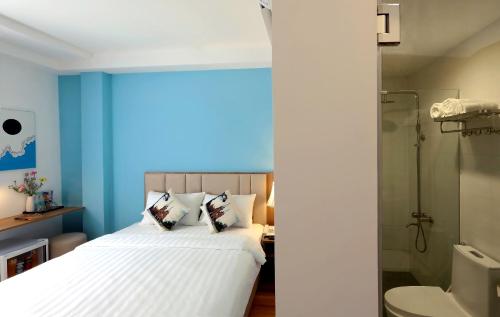 a bedroom with blue walls and a bed with pillows at Sogo Hotel Saigon in Ho Chi Minh City