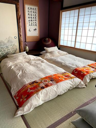 two twin beds in a room with a window at Okiya Guest House & Tapas Bar in Kiryu