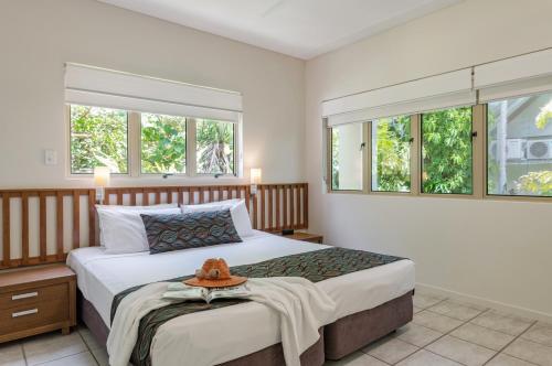 a bedroom with a bed with a hat on it at Silkari Reflections of Port Douglas in Port Douglas
