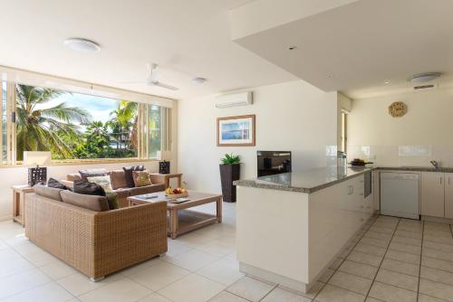 an open kitchen and living room with a couch at Silkari Reflections of Port Douglas in Port Douglas