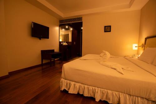Pokój hotelowy z łóżkiem i biurkiem w obiekcie Grand Gardenia w mieście Tiruchchirāppalli