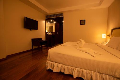 a hotel room with a bed and a desk at Grand Gardenia in Tiruchchirāppalli