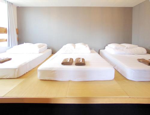 three beds with slippers on them in a room at Hostel 1889 in Fujiyoshida