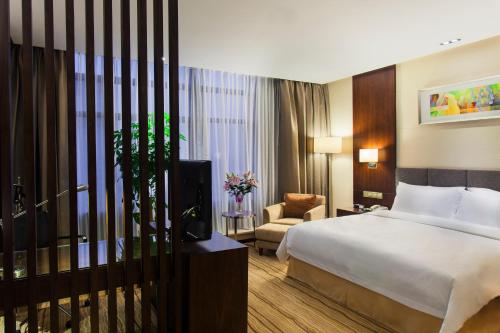 um quarto de hotel com uma cama e uma cadeira em Holiday Inn Taicang City Centre, an IHG Hotel em Taicang