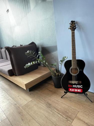 a guitar sitting next to a couch in a room at Ibis Sofia Airport Hotel in Sofia