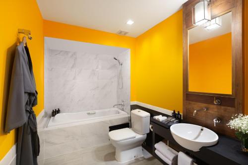 a bathroom with yellow walls and a toilet and a sink at RELO' The Urban Escape - Huahin in Cha Am