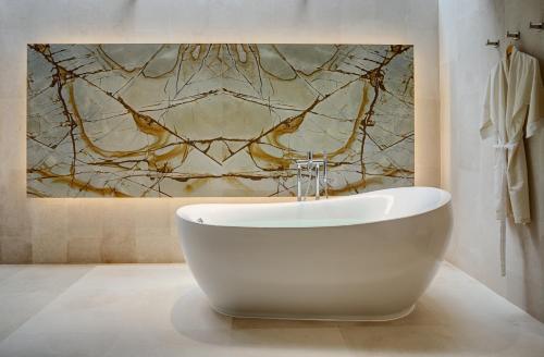 a white bath tub in a bathroom with a painting at RELO' The Urban Escape - Huahin in Cha Am
