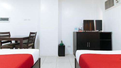 a room with two beds and a table and a tv at RedDoorz Plus Evangelista Street Makati in Manila
