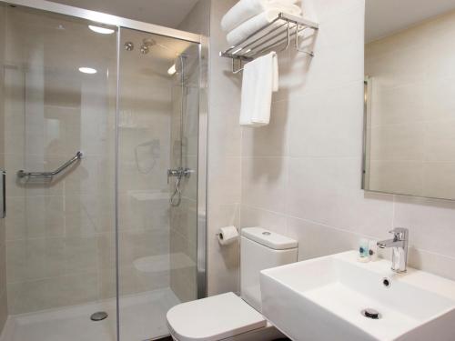 een badkamer met een douche, een toilet en een wastafel bij Hotel Lux Santiago in Santiago de Compostela