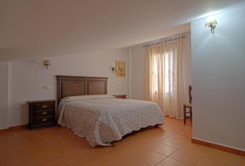 ein Schlafzimmer mit einem Bett, einer Kommode und einem Fenster in der Unterkunft Casa Concepción in Grazalema