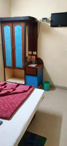 a bedroom with a bed and a dresser and a tv at Vamoose Balaji Inn in Hoshangābād