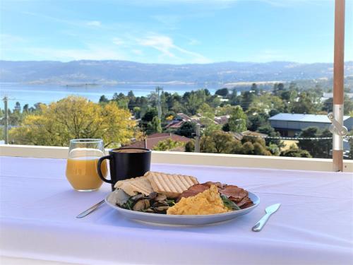 un piatto di cibo su un tavolo con una tazza di succo d'arancia di Vikas a Jindabyne